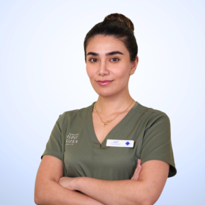 صورة احترافية للأستاذة تينا، فنية الليزر وأخصائية العناية التجميلية في عيادة أزورا بمسقط، ترتدي الزي الرسمي للعيادة وتقدم خدمات الليزر والعناية التجميلية باحترافية.